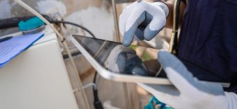 Close up hand engineer working use digital tablet report or analysis AI manufacturing system industrial plant. Environment technician check clean air pollution reduction for sustainable ESG.Electrical