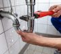 Male Plumber's Hand Repairing Sink Pipe Leakage With Adjustable Wrench