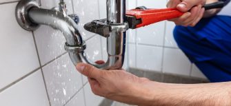 Male Plumber's Hand Repairing Sink Pipe Leakage With Adjustable Wrench