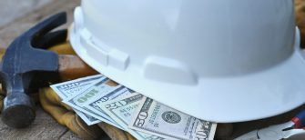 Hard hat with construction tools and cash money - concept for building cost or fraud, scam, bribes