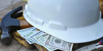 Hard hat with construction tools and cash money - concept for building cost or fraud, scam, bribes