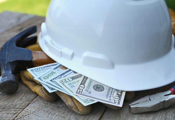 Hard hat with construction tools and cash money - concept for building cost or fraud, scam, bribes