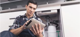 plumbing contractor looking at his ipad and completing a job