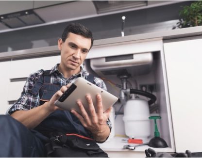 plumbing contractor looking at his ipad and completing a job