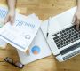 Topview of office desk with documents and laptop. Businesswoman working on paperwork.