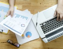Topview of office desk with documents and laptop. Businesswoman working on paperwork.