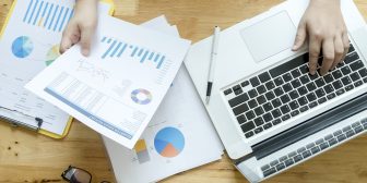 Topview of office desk with documents and laptop. Businesswoman working on paperwork.