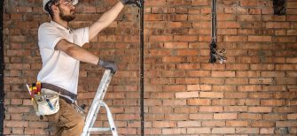 Electrician with tools, working on a construction site. Repair and handyman concept. House and house reconstruction. SSUCv3H4sIAAAAAAAACpyRz27DIAzG75P2DhHnRmr+ttmrVDs44CaoFCogm6aq7z4DYeK8G/7Z/uzPPN/fqorN4CRnH9UzRBRLpTbnLXhpNOHjYecWtUBbEhTSGytBlXAGz1cNdySoN6UCfsUkcx785tCFYTvi4HEhjQT/JNJGlxRXORGT1EEpxg4Fc9scWUZJ/F+d6fGZ3cCCmv/EhQsjFhVCMnJJpez27dHeS2uwCWkKV1+GgwoFXaH0sJJLvRRtxq/xyrmNm017G1ZgbTPl5Zky5gGzCle+kixmvoJz1CEyL2Zx+lZzL0Zp46OH/SRM0GeEsOnapm+HYTr14+lEUbcXpA9cJenEjbIQxfwmRelehg3YNJ6vneBT3R3bse4HMdZwPkLNkUPTNu25GZBu//oFAAD//wMAxplQV4oCAAA=