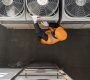 An HVAC technician works on an air conditioning unit