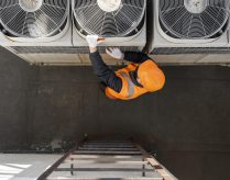An HVAC technician works on an air conditioning unit
