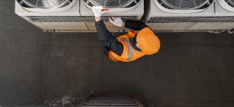 An HVAC technician works on an air conditioning unit