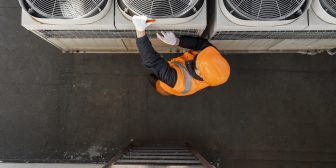 An HVAC technician works on an air conditioning unit