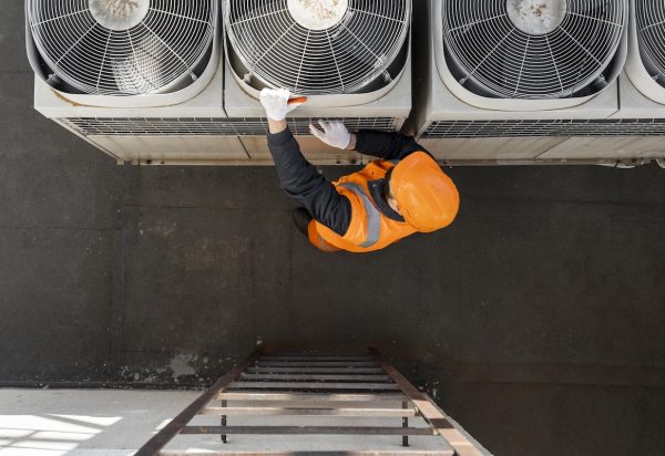 An HVAC technician works on an air conditioning unit