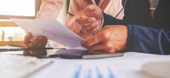 Business concept. Business people discussing the charts and graphs showing the results of their successful teamwork. Selective focus.