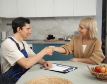 male-plumber-working-with-client-fix-kitchen-problems