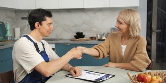 male-plumber-working-with-client-fix-kitchen-problems