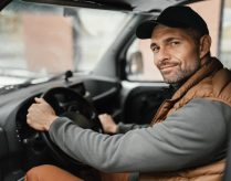 an hvac plumbing technician wearing a vest drives a work van, the text reads customer spotlight: how Leigh's heating and cooling succeeds with WEX FSM