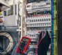 Man, an electrical technician working in a switchboard with fuses. Installation and connection of electrical equipment. Professional uses a tablet.