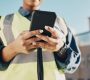 Phone, construction worker hands and person typing, networking or search info about inspection, maintenance or building. Cellphone communication, closeup builder or engineer research architecture.