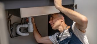 Plumber, repair. Experienced attentive middle-aged man carefully examining bottom of kitchen sink touching pipe with his hand diagnosing problem SSUCv3H4sIAAAAAAAACnRSQU7DMBC8I/GHyOdGSuskJf0BBwT3isPG3ramrl3ZThGq+DvrOEY+wC07szs748398aGq2AheCbar7rGiWmk9+eAgKGsIblYL7tBIdCVyc7xvSgClCtYp0CU4QhAnAxck0ExaR/h7JpkPECaPPm5fIAEBj6SRwF+JZHGf6ioTM0kTRLFnE9Ap6zxbFaSfxki+jh8ogmeZScv+UXpDe9X4l8yL8gK1BoN2KsTSx3sODEc04mvOVGR1qBFS1n1qZedPsnwp08MklS2C36wAHRt4oXR1SihzLMZsOM2XyWPCTia4aIHlGExbe4WRcu2qA2lixk/gPbXLjBeLBP0H9lLsMTbMARZVJulYsVzzzRMf+NB3XbvhfbtdLw3pwCdFOrOdLES1OCtZRlfRAdvIrYRDu61F0/O6HUHUwwBQd13Hh0PT4yg5Pfz3DwAAAP//AwCsHV1xuwIAAA==