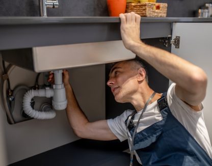 Plumber, repair. Experienced attentive middle-aged man carefully examining bottom of kitchen sink touching pipe with his hand diagnosing problem SSUCv3H4sIAAAAAAAACnRSQU7DMBC8I/GHyOdGSuskJf0BBwT3isPG3ramrl3ZThGq+DvrOEY+wC07szs748398aGq2AheCbar7rGiWmk9+eAgKGsIblYL7tBIdCVyc7xvSgClCtYp0CU4QhAnAxck0ExaR/h7JpkPECaPPm5fIAEBj6SRwF+JZHGf6ioTM0kTRLFnE9Ap6zxbFaSfxki+jh8ogmeZScv+UXpDe9X4l8yL8gK1BoN2KsTSx3sODEc04mvOVGR1qBFS1n1qZedPsnwp08MklS2C36wAHRt4oXR1SihzLMZsOM2XyWPCTia4aIHlGExbe4WRcu2qA2lixk/gPbXLjBeLBP0H9lLsMTbMARZVJulYsVzzzRMf+NB3XbvhfbtdLw3pwCdFOrOdLES1OCtZRlfRAdvIrYRDu61F0/O6HUHUwwBQd13Hh0PT4yg5Pfz3DwAAAP//AwCsHV1xuwIAAA==