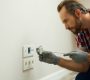 Portrait of electrician wearing protective gloves, using a screwdriver while installing new plug socket in a house. Electrical maintenance, repair service concept SSUCv3H4sIAAAAAAAEAH2Rz04DIRDG7ya+w4ZzN1lbKru+g9F742GAsYul0PBH0zR9d2EpysF4Y37fzAcfc7m/6zrCwStBnrpLrlKttI4+OAjKmoSH1Y07NBJdS1CqYJ0C3UIOQcwGjpigiVpnfF1E4gOE6NHny25IQMB98ijwx6K8aFfqrgqLmCaSRF7RnjSSVaP4yLPyjIZUel39Y/HCP1AE/6eH8gK1BoM2+l+3cnirUWGPRpyXNE1KhxqhpNyVVnL4CuiObW6IUtkm8qcVoHPDpnE6OSWU2TdjNszLCuqYsNEEl59AagyirT0B1/n/35MnVj6D96ldVt5cJNLC7bG5x9iwBLi5EpnWlMuHzXq7ptM4PI7baZzYSEldrRUHJduIZduzSpI7N1zlFxBKx4kDoz1bA+upHFjPcQv9o2AIfKI4MJk+/voN5K/JfaQCAAA=