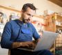 Portrait of mature worker using laptop in carpenters workshop interior, copy space