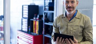 Portrait of smiling mechanic using digital tablet in repair shop
