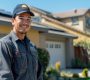 an hvac worker stands in front of a house smiling