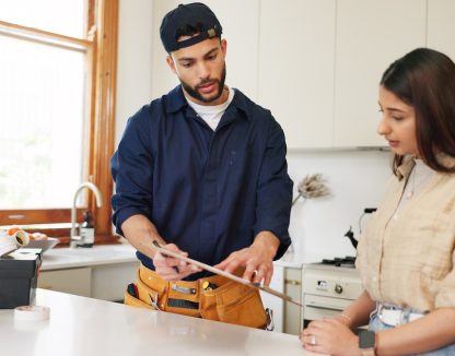Woman, home and plumber with contract on clipboard for maintenance service, information and repairs. Kitchen, discussion and man with notes in checklist for renovation, inspection or customer invoice.