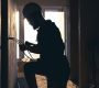 A construction electrician cuts a voltage cable during a repair, silhouette in the light of the setting sun.