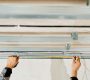 Worker's hands measure and adjust a metal profile for mounting a plasterboard ceiling frame, close-up, selective focus in the hands of a specialist. Industrial renovation and renovation